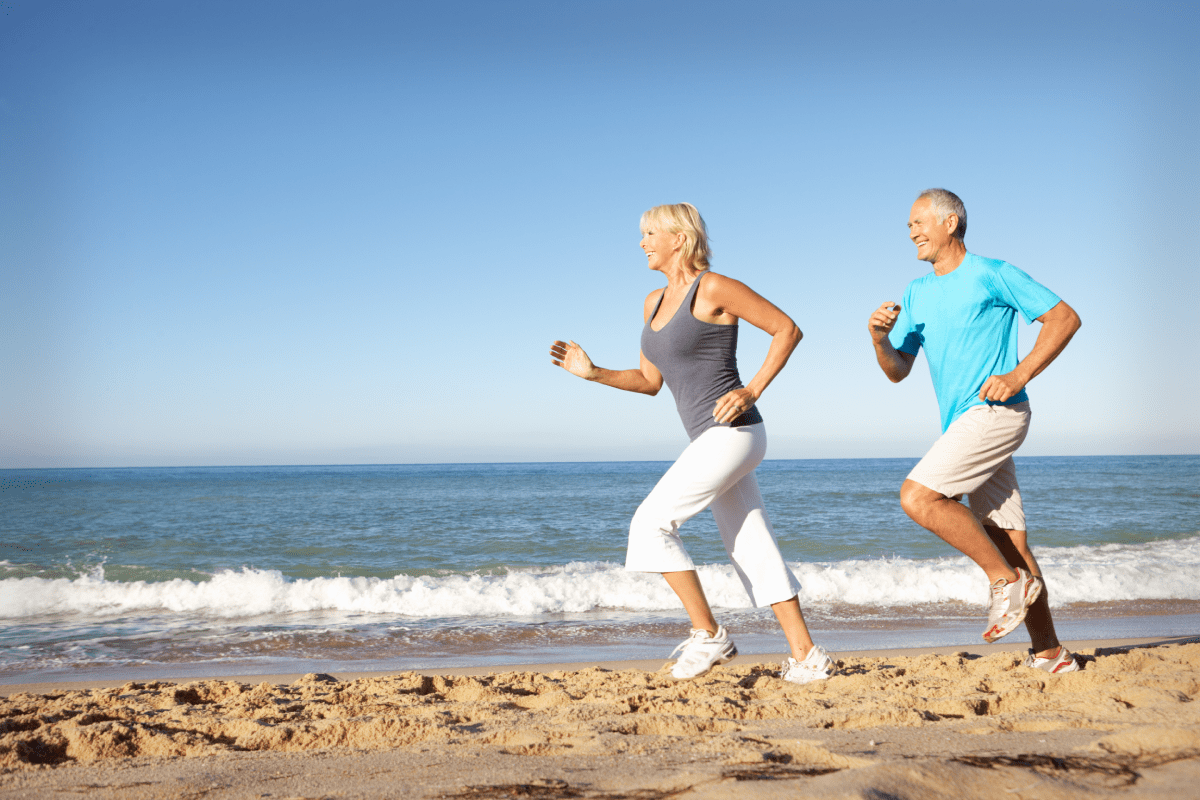 Senior Couple Running Along Beach